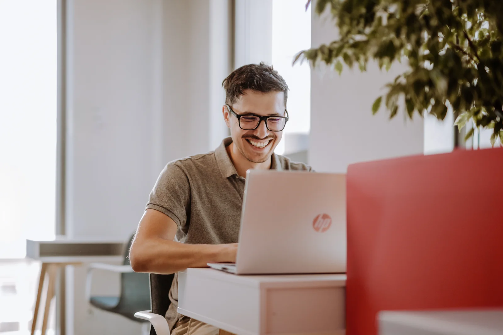 A smiling Xelerit developer working on a laptop in the office